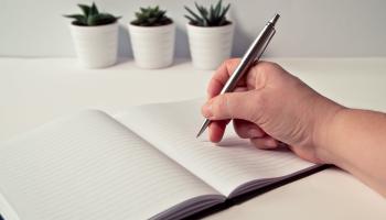 Person Holding Silver Retractable Pen in White Ruled Book