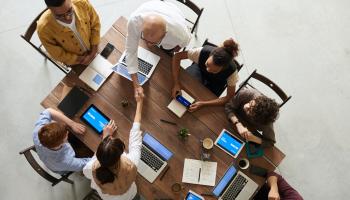 People shaking hands over a conference table in an office setting