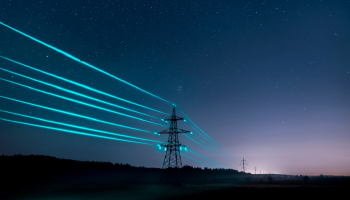Electricity transmission towers with glowing wires against the starry sky